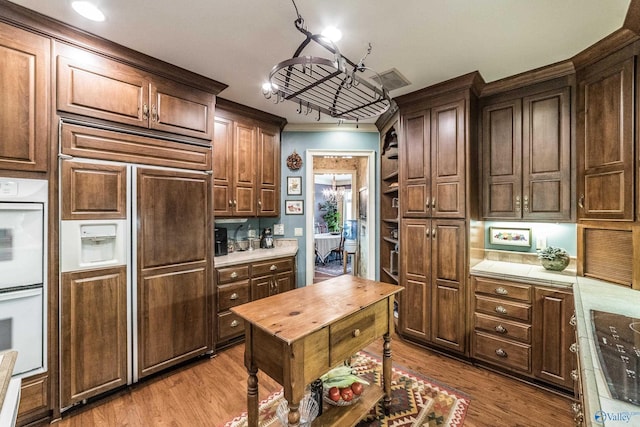 kitchen featuring crown molding, light hardwood / wood-style flooring, white double oven, paneled fridge, and tile countertops