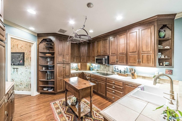 kitchen with sink, crown molding, tile countertops, black electric cooktop, and light hardwood / wood-style floors