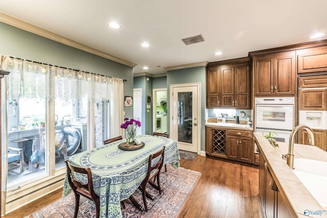 kitchen featuring double oven, sink, paneled built in refrigerator, ornamental molding, and dark wood-type flooring