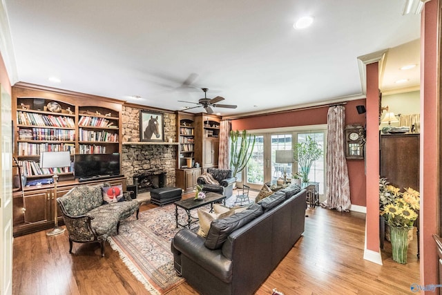 living room featuring hardwood / wood-style flooring, ceiling fan, ornamental molding, and a fireplace