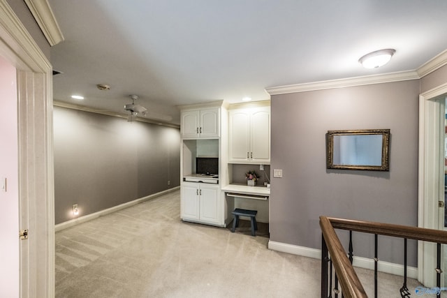 carpeted home office with ornamental molding, built in desk, and ceiling fan