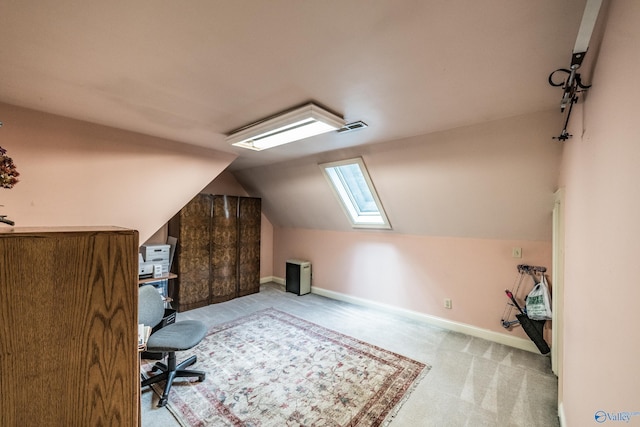 office area with vaulted ceiling with skylight and light carpet