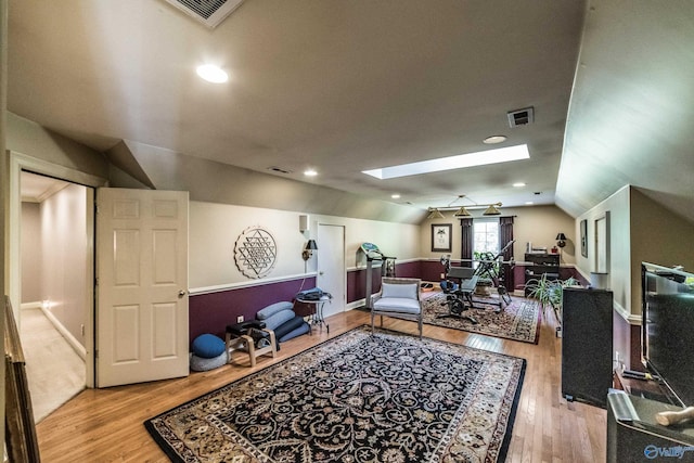 interior space featuring lofted ceiling with skylight and light hardwood / wood-style floors