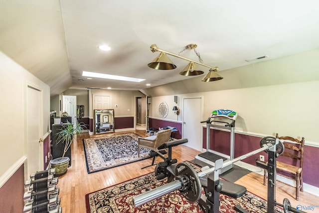 workout area featuring hardwood / wood-style flooring and lofted ceiling with skylight