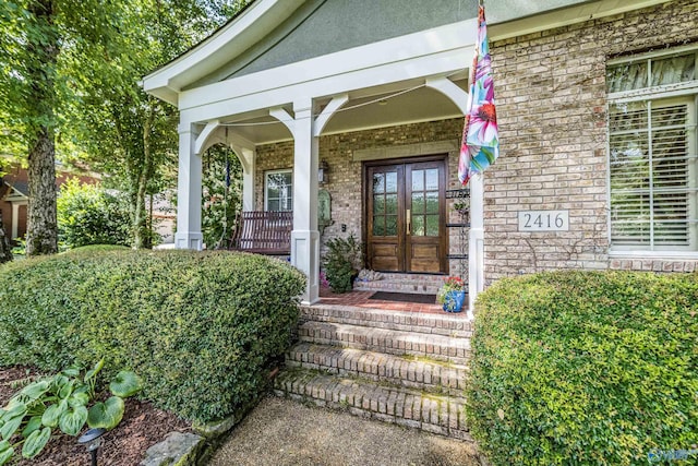 view of exterior entry with a porch and french doors