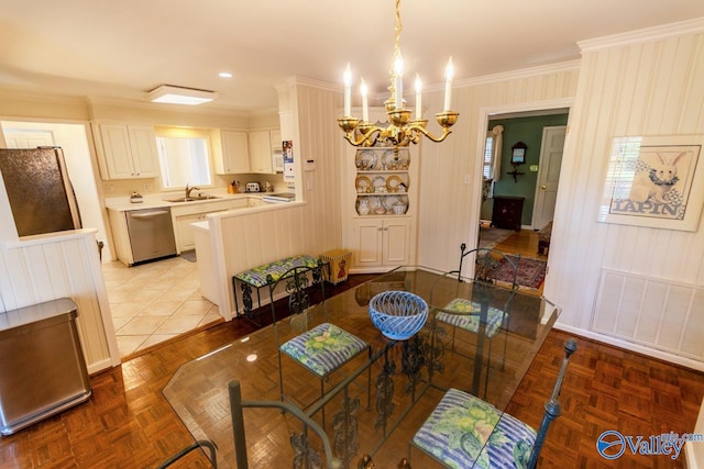 dining area with sink, light parquet flooring, ornamental molding, and a notable chandelier