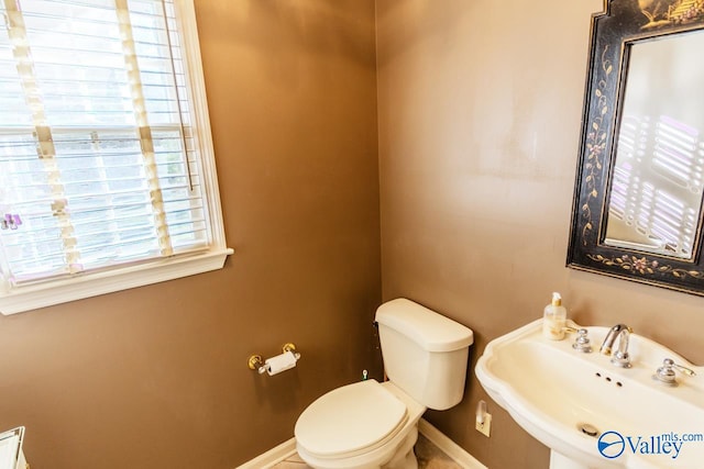 bathroom featuring plenty of natural light, toilet, and sink