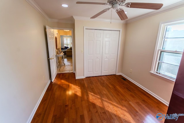 unfurnished bedroom featuring ceiling fan, dark hardwood / wood-style flooring, crown molding, and a closet