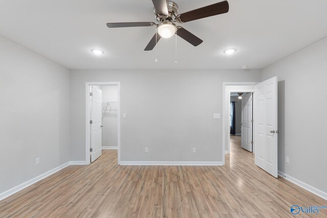 interior space featuring a spacious closet, light hardwood / wood-style floors, a closet, and ceiling fan