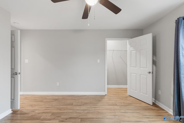 unfurnished bedroom with ceiling fan, light hardwood / wood-style floors, a spacious closet, and a closet