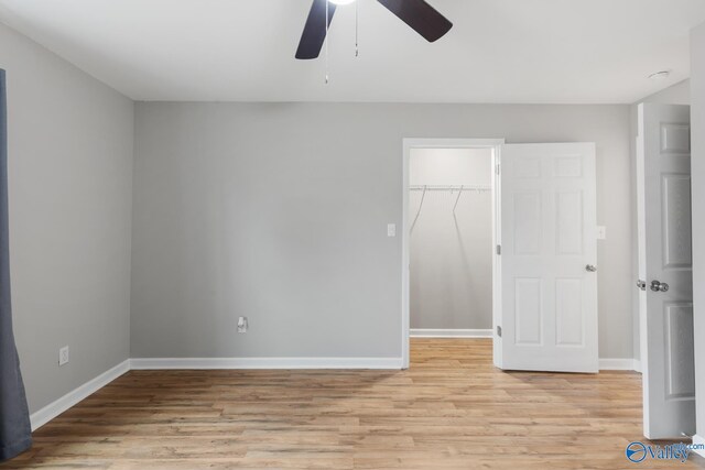 unfurnished bedroom featuring a closet, ceiling fan, light hardwood / wood-style flooring, and a spacious closet