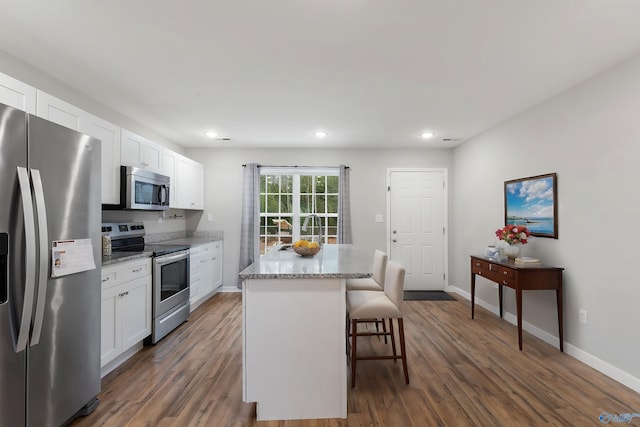 kitchen featuring light stone countertops, white cabinetry, stainless steel appliances, and a kitchen island