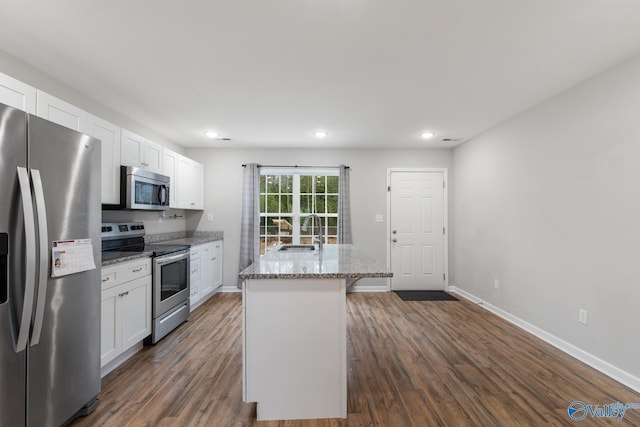 kitchen featuring light stone countertops, white cabinets, a kitchen island, dark hardwood / wood-style flooring, and stainless steel appliances