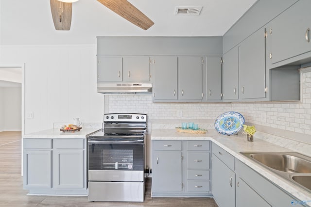 kitchen featuring tasteful backsplash, electric range, gray cabinets, light countertops, and under cabinet range hood