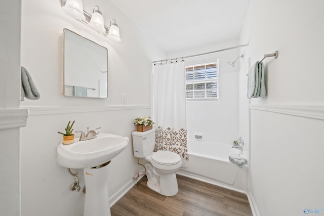 full bath with shower / bath combo, wood finished floors, toilet, and baseboards