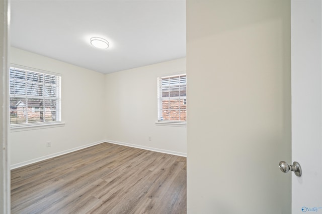 unfurnished room with baseboards and wood finished floors