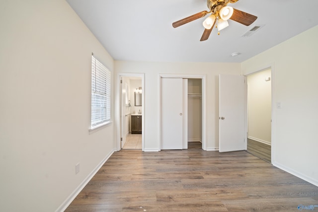 unfurnished bedroom with a closet, visible vents, connected bathroom, and wood finished floors