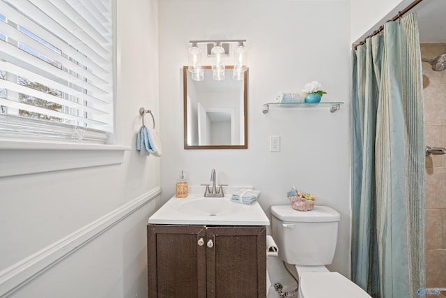 full bath featuring toilet, a tile shower, and vanity