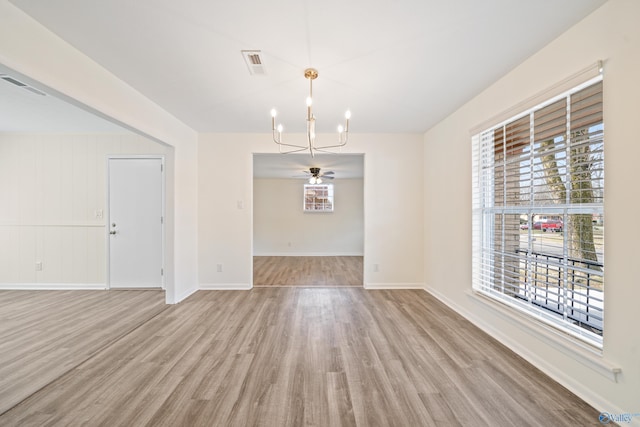 unfurnished dining area featuring light wood-style flooring, visible vents, baseboards, and ceiling fan with notable chandelier