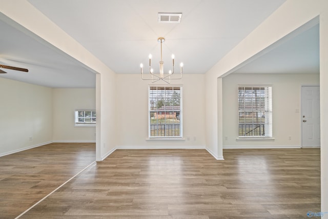 unfurnished dining area with baseboards, visible vents, wood finished floors, and ceiling fan with notable chandelier