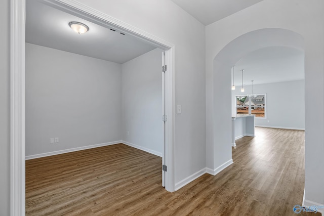 interior space with baseboards, arched walkways, and wood finished floors