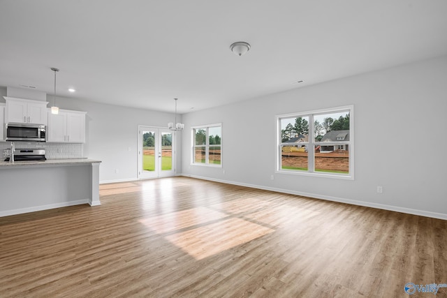 unfurnished living room featuring light wood-type flooring, french doors, baseboards, and recessed lighting