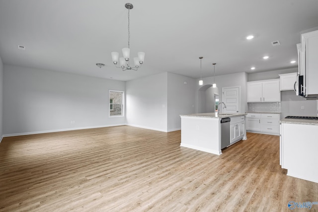 kitchen featuring open floor plan, a kitchen island with sink, stainless steel appliances, light countertops, and white cabinetry