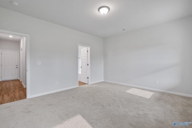 empty room featuring baseboards and light colored carpet