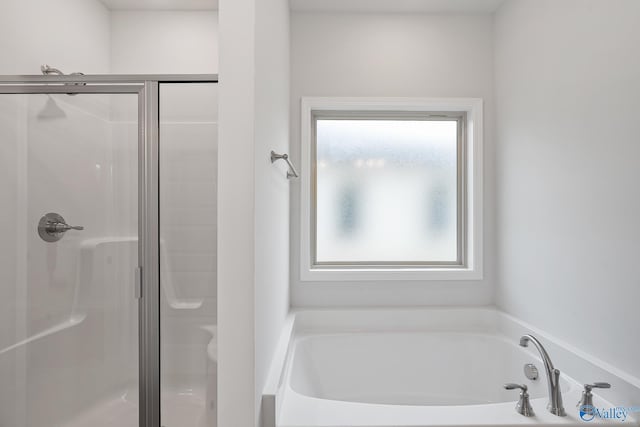 bathroom with a stall shower and a garden tub