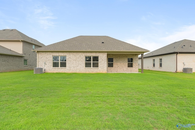 back of house with brick siding, a yard, and central AC unit