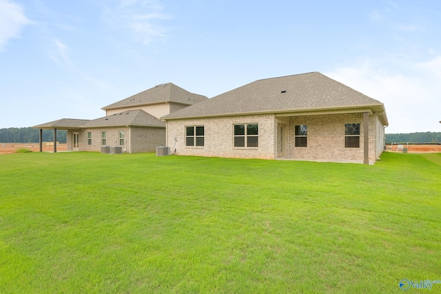 back of property with roof with shingles, cooling unit, a lawn, and brick siding