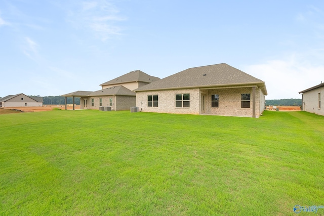 back of house with brick siding, a lawn, and central AC unit