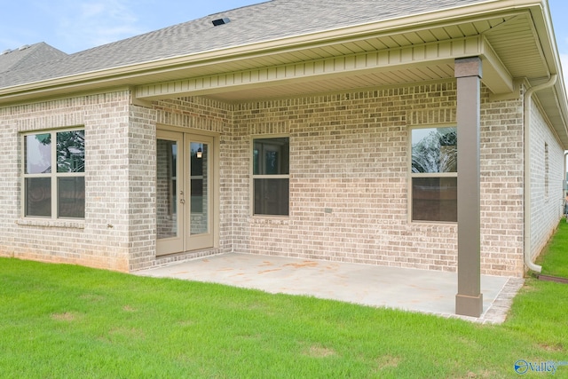 back of property featuring a shingled roof, french doors, a patio area, and a lawn