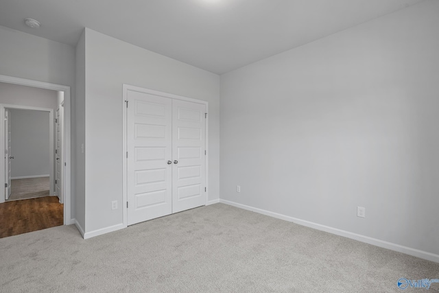 unfurnished bedroom with baseboards, a closet, and light colored carpet