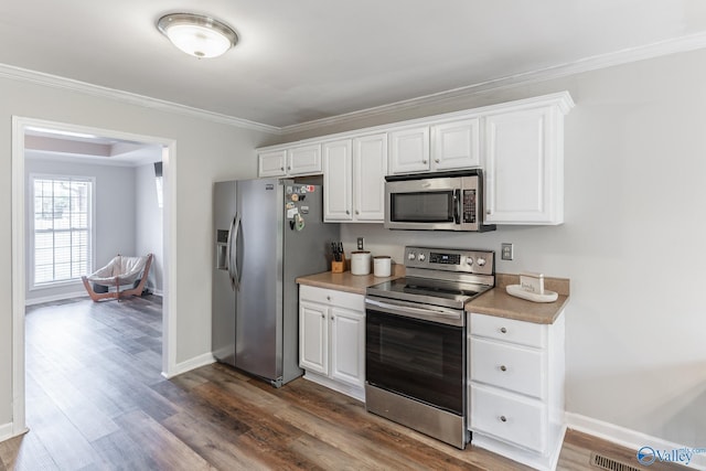 kitchen with white cabinetry, appliances with stainless steel finishes, ornamental molding, and dark wood-type flooring