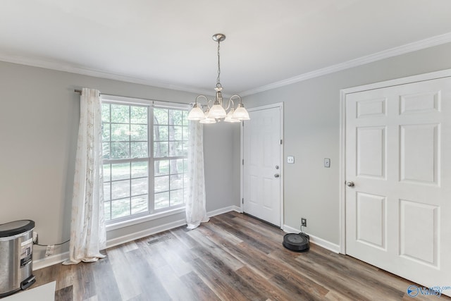 unfurnished dining area featuring dark wood-type flooring, ornamental molding, and an inviting chandelier