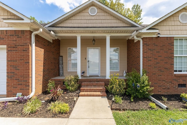 view of exterior entry featuring a porch and a garage