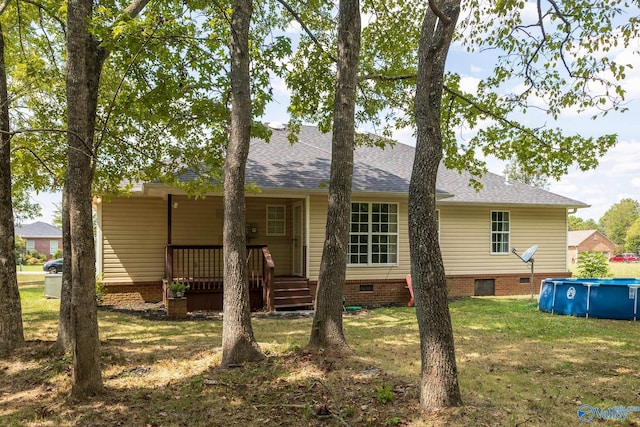 back of property with a lawn, crawl space, an outdoor pool, and roof with shingles