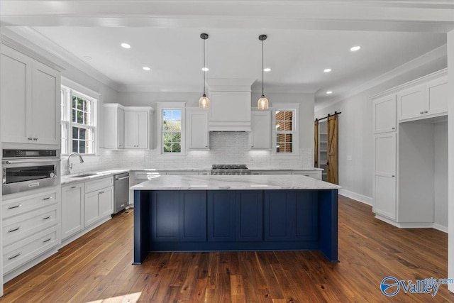 kitchen with stainless steel appliances, white cabinetry, a sink, and a barn door