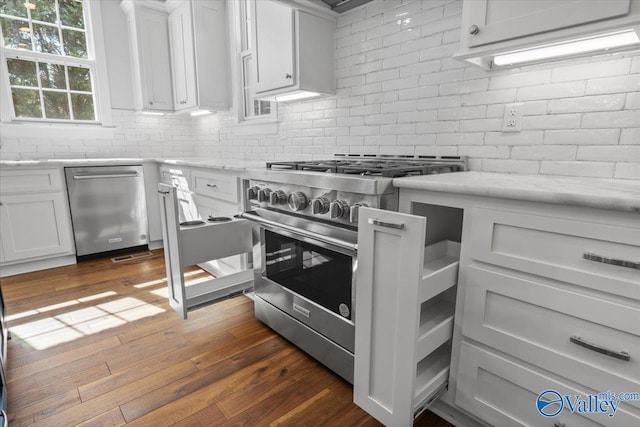 kitchen featuring decorative backsplash, appliances with stainless steel finishes, dark wood-type flooring, white cabinetry, and light stone countertops