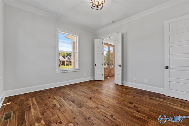 unfurnished bedroom featuring dark wood-style flooring, visible vents, baseboards, ensuite bath, and crown molding