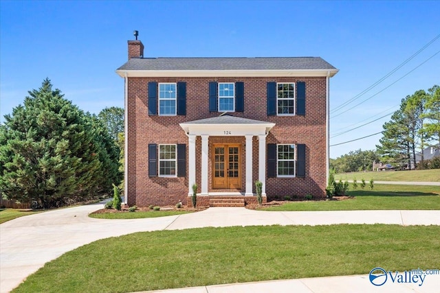 view of front of house with a front yard, brick siding, and a chimney