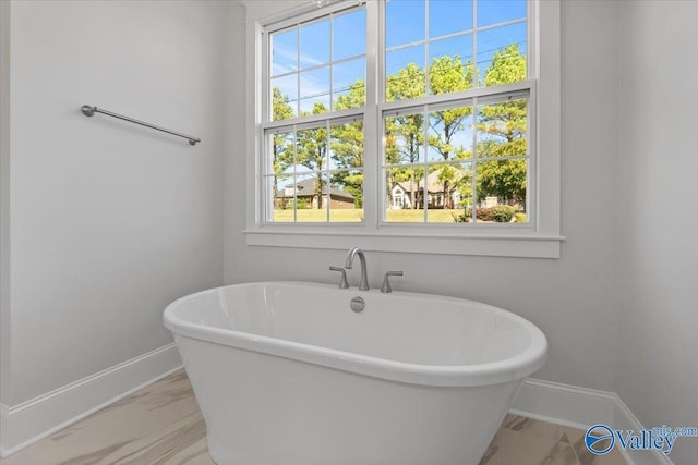 full bath featuring a freestanding tub and baseboards