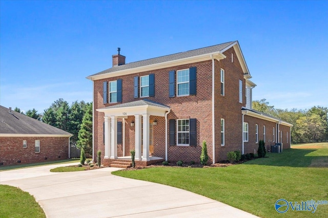 view of front of home with central air condition unit, brick siding, concrete driveway, a front lawn, and a chimney