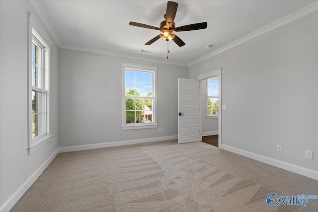 empty room featuring carpet, baseboards, visible vents, and crown molding