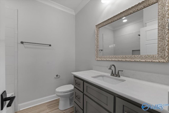 bathroom with toilet, wood finished floors, vanity, baseboards, and ornamental molding