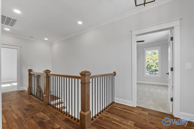 hall featuring ornamental molding, wood finished floors, visible vents, and baseboards