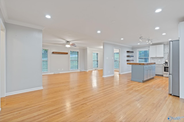 kitchen featuring decorative backsplash, ornamental molding, appliances with stainless steel finishes, light hardwood / wood-style floors, and white cabinetry