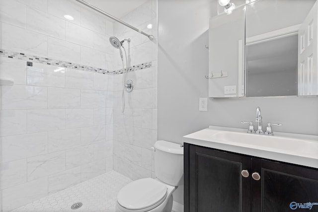 bathroom with tiled shower, vanity, and toilet