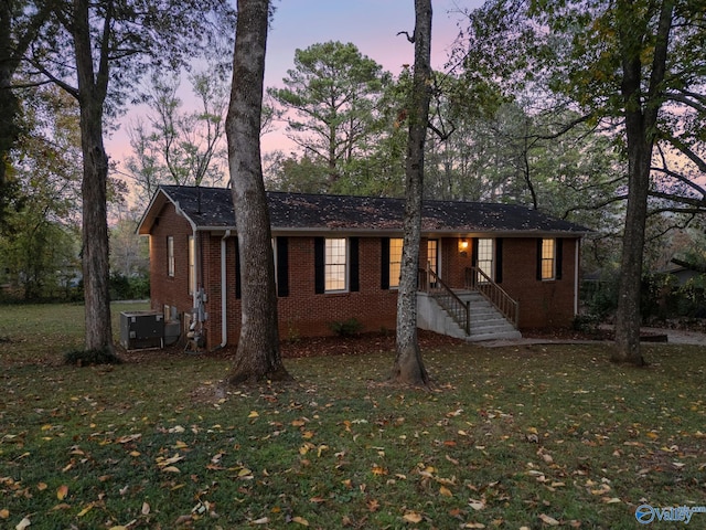 ranch-style home featuring a yard and central AC unit